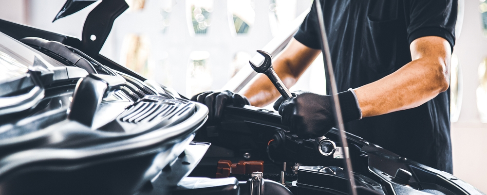 Close-up of a mechanic skillfully repairing a car engine, showcasing expertise in modern automotive maintenance.